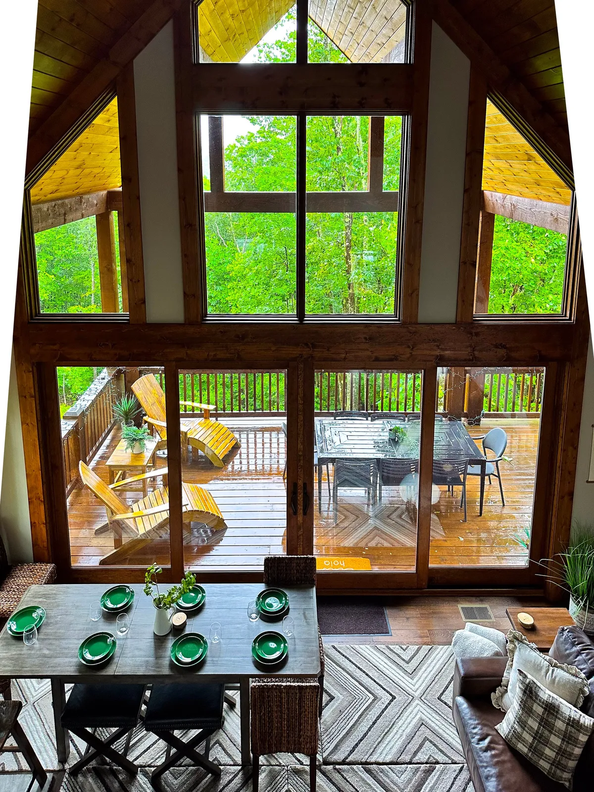 A bright and inviting dining area featuring large windows with panoramic views, a central dining table ready for special occasions, and direct access to an outdoor deck—blurring the line between indoor comfort and fresh mountain air.