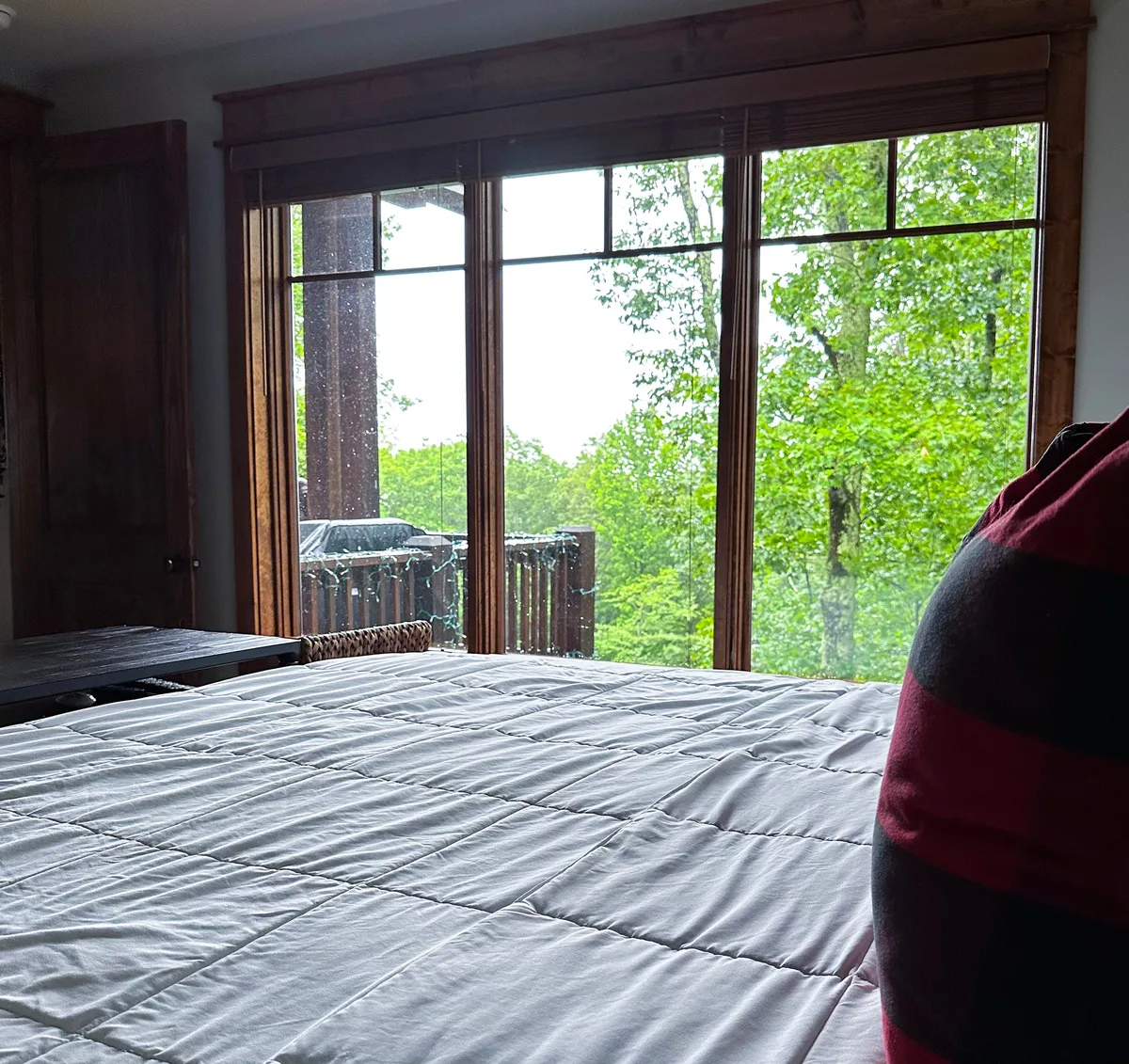 This tranquil bedroom is bathed in natural light from large windows overlooking lush greenery. The neatly made king bed and warm wooden furniture create a serene and luxurious atmosphere, inviting restful sleep and morning relaxation.